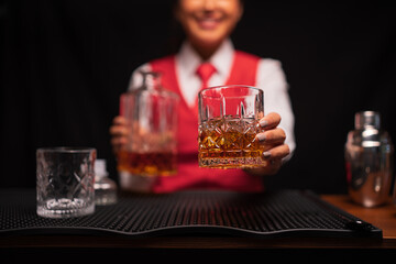 Bartender woman pours whiskey into a glass in a restaurant.	