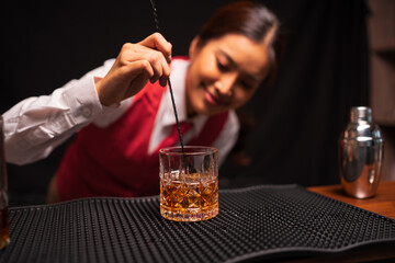 Bartender woman pours whiskey into a glass in a restaurant.	