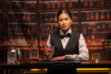 Bartender woman pours whiskey into a glass in a restaurant.	