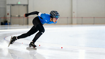 Speed skater in motion on indoor ice rink wearing protective gear and racing suit