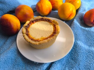 freshly baked bun with sour cream filling on a white plate surrounded by ripe nectarines.