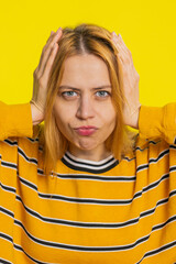 Don't want to hear, listen. Frustrated annoyed irritated young blonde woman covering ears gesturing no, avoiding advice ignoring unpleasant noise loud voices. Girl isolated on yellow background