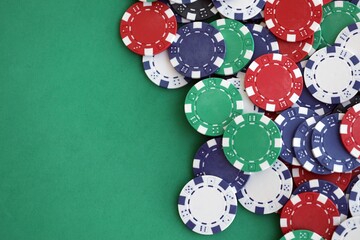 Casino gaming background with stacks of betting chips of different colors on green gaming mat