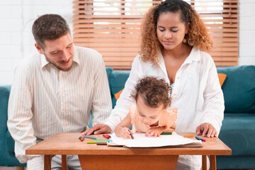 Happy parents playing with their adorable baby at home. Mom and dad looking at their baby who drawing on paper with pencil in cozy living room. Creative education. Early development	
