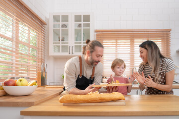Beautiful cute family having fun while cooking together in the kitchen at home. Family with child in kitchen having breakfast.	