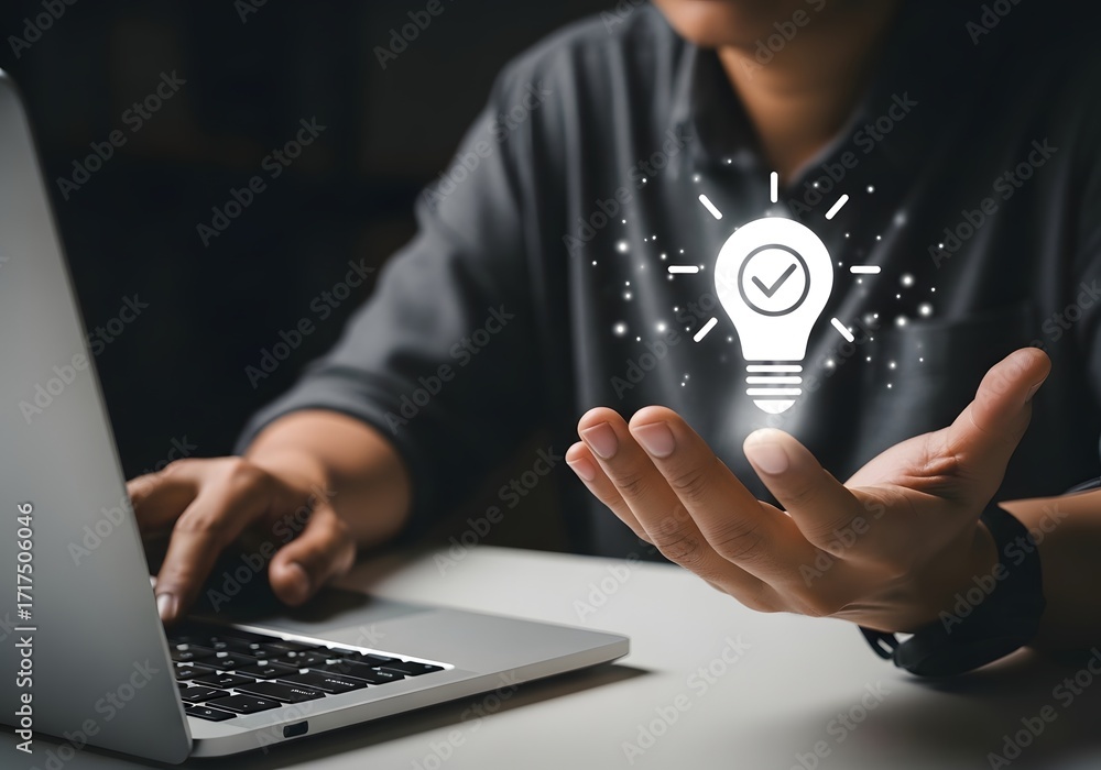 Poster man working on laptop with lightbulb idea graphic hovering above his hand in a dark setting