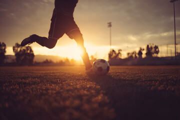 Soccer Player Mid-Kick on Grassy Field with Backlit Action
