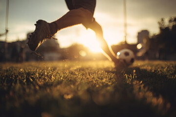 Soccer Player Mid-Kick on Grassy Field with Backlit Action