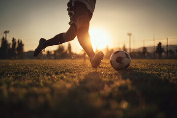 Soccer Player Mid-Kick on Grassy Field with Backlit Action