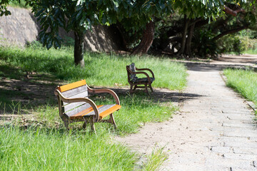 晴れた日の緑のある公園に並ぶ黄色いベンチ
