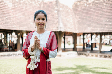Woman in traditional attire performing a respectful greeting in a historic courtyard, showcasing...