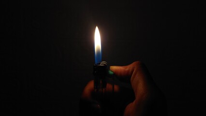 Close-up photo of a hand lighting a gas lighter in a dark room, creating a small flame that brightens the darkness. Dramatic scene symbolizing light, hope, survival. cinematic projects, storytelling