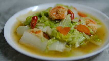 Stir fried napa cabbage with shrimps in a white plate.