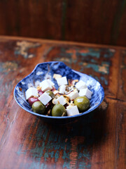 Green and kalamata olives and feta cheese on rustic wooden background. Soft focus.	