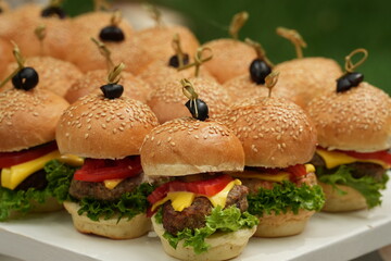 a tray of mini burgers with olives and cheese