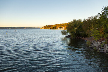 Small sailboats anchored in a St. Lawrence river cove during a fall morning, with a cape covered in...
