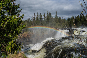 Ristafallet Waterfall in Sweden with a rainbow in the sky.