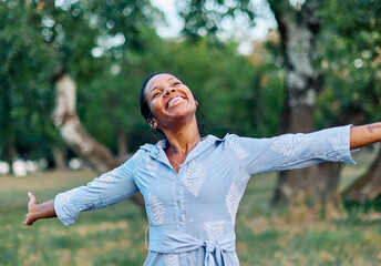 Happy young black woman meditating and daydreaming and relaxing and having fun in nature outdoors
