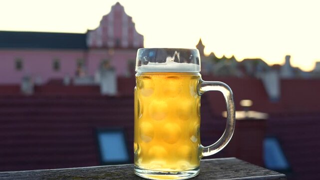 Beer mug on table with blurred city rooftops summer evening