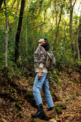 Fototapeta premium woman in a sweater and a backpack on her back travels. on a hike in the mountains. Young happy tourist woman relaxing in nature