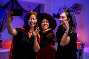 Diverse women friends celebrating Halloween party, posing for a selfie in costumes, enjoying holiday festivities