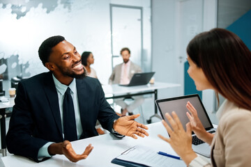 Diverse business colleagues collaborating and smiling during a discussion in a modern office