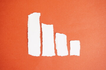 Four paper pieces of varying lengths in the form of a bar chart in descending order on an orange background