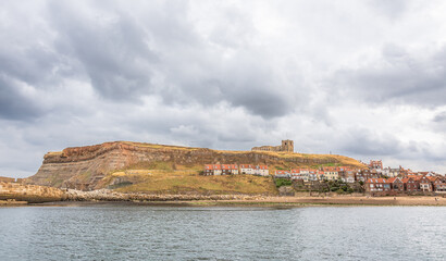 A seaside panorama with a church on a hill and houses beneath.