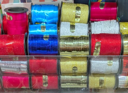 Expositor de tienda con carretes de cinta en varios colores y texturas para manualidades y proyectos de bricolaje.