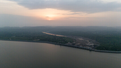 Fototapeta premium Aerial view of Mahi Dam, Banswara, Rajasthan during monsoon, showing the reservoir and villages with the sun setting over the village side