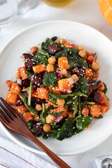 Roasted pumpkin beetroot chickpea salad in a plate with fork. Top view.