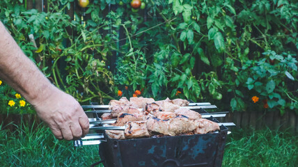Shashlik on skewers is being cooked on charcoal in a barbecue close-up.