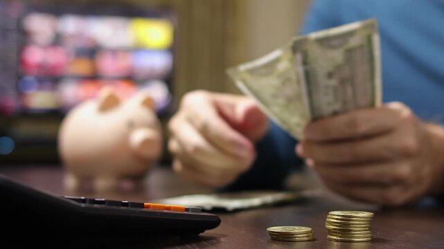 Close up view of man hands, calculator, Indian rupee coins and banknotes (INR). Concept of saving money for retirement, cash settlement, financial goals, success, literacy and income planning in India