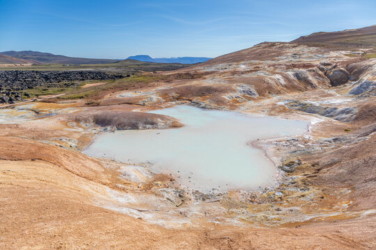 Mare aux couleurs laiteuses sur la colline de Leirhnj&uacute;kur, entour&eacute;e d'un champ de lave du volcan Krafla, dans le nord de l'Islande