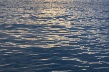 A close-up, full-frame shot of the ocean surface with light glinting off small, dark ripples.
