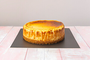 A photograph of a dulce de leche cheesecake with an intense caramel curl on the top and toasted...
