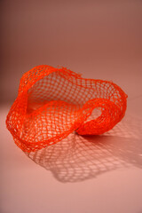 Fototapeta premium Orange plastic net creating abstract shadow pattern