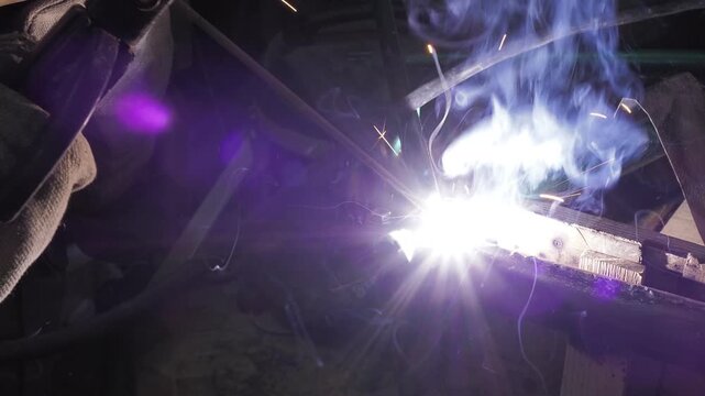Workshop. A welder uses an electrode to weld a pipe onto the frame of an old bicycle.
