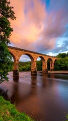 Stone arch bridge at sunset over river