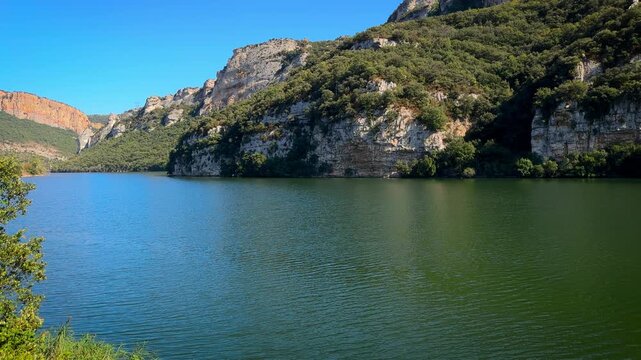 Scenic view of the Sobron Reservoir on the Ebro River, located between Alava and Burgos, Spain. Surrounded by green mountains and dramatic rock formations, this water landscape is a popular