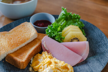 Breakfast with toast, scrambled eggs, ham and kiwi
