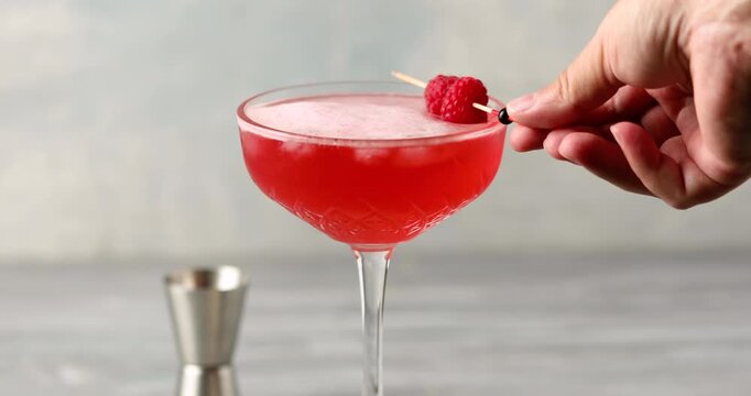 Alcoholic cocktail clover club with raspberries in a cocktail glass on the table.