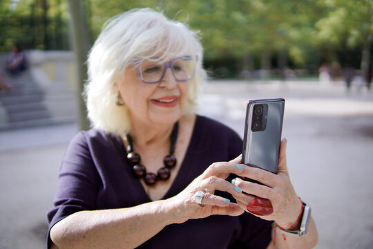 Senior woman taking selfie with smartphone in park