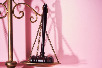 libra scale and gavel hammer against pink background.