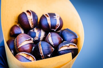 Warm, roasted chestnuts (Maronen) presented invitingly in a rustic paper cone, evoking autumn comfort and street food delight.