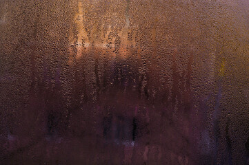 Wet glass window with water droplets, blurring view. Condensation creates natural abstract patterns. Close-up of foggy window covered in tiny water drops. Blurred damp glass surface background.