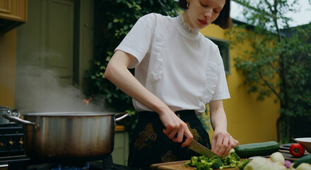Young woman chopping vegetables in a cozy kitchen, surrounded by fresh ingredients