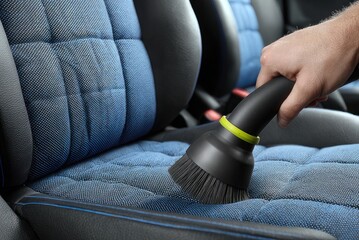Obraz premium Hand cleaning blue car seat with vacuum brush attachment