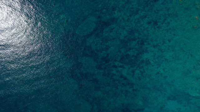 Aerial view of the azure surface of the Mediterranean Sea. The water is crystal clear and blue. Ideal for background, texture and pattern. - Powered by Adobe