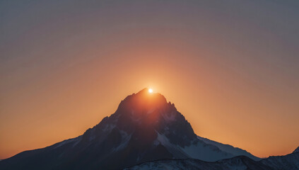Sun rising behind mountain peak, minimalist silhouette with glowing sky